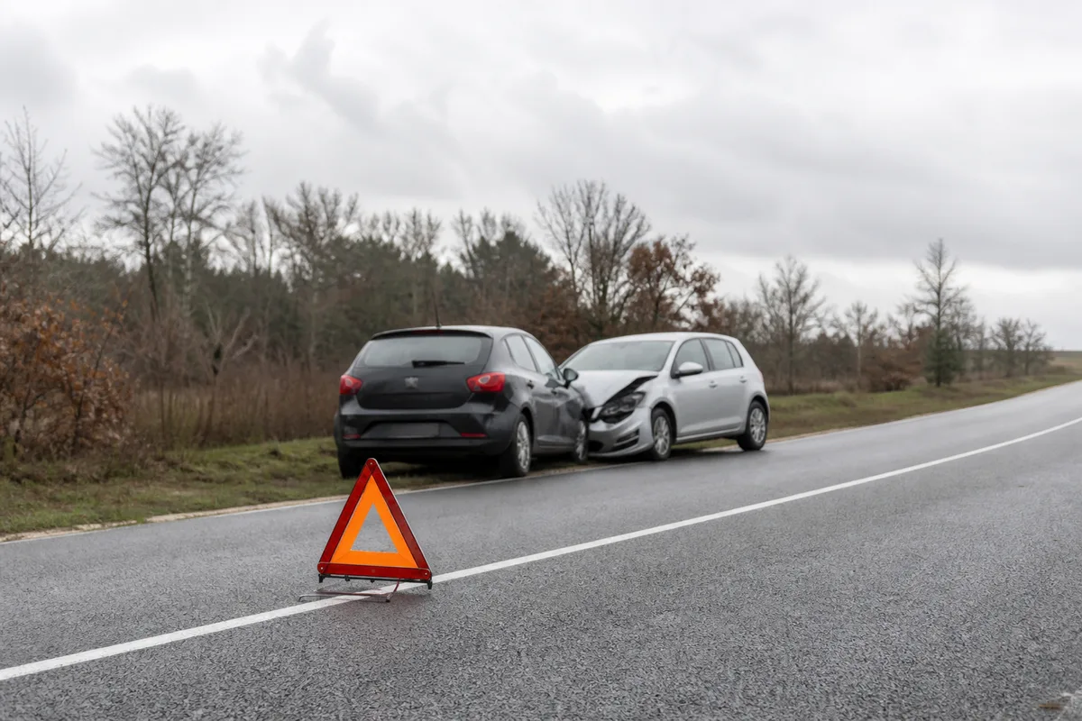 Deux véhicules accidentés sur le bas-côté d&rsquo;une route de campagne, avec triangle de signalisation posé devant