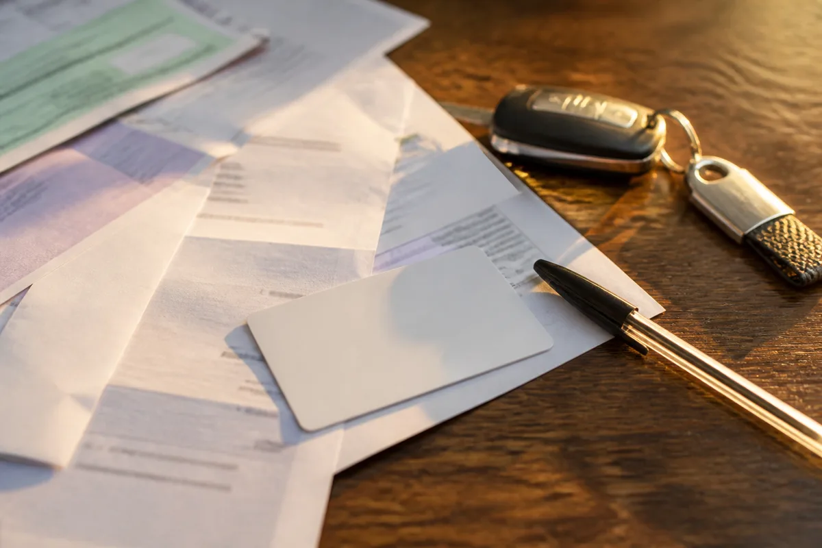 Carte grise, permis de conduire et relevé d’information posés sur une table avec un stylo